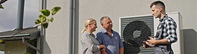 Monteur und ein Paar vor einer Wärmepumpe