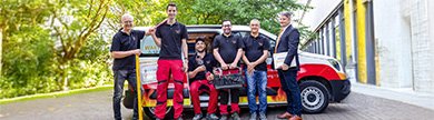 Monteursteam steht vor Firmenfahrzeug