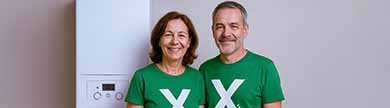 Zwei Personen mit einem X auf grünen Shirts stehen vor einer Gasheizung