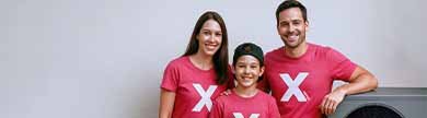 Familie mit einem X auf roten Shirts stehen vor einer Wärmepumpe